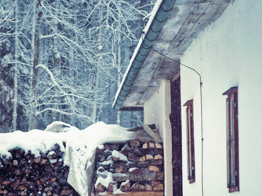 Firewood stacked against a house in falling snow